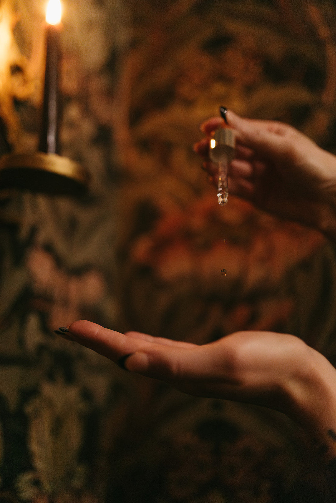 Glass dropper of serum against wallpaper and candle in background