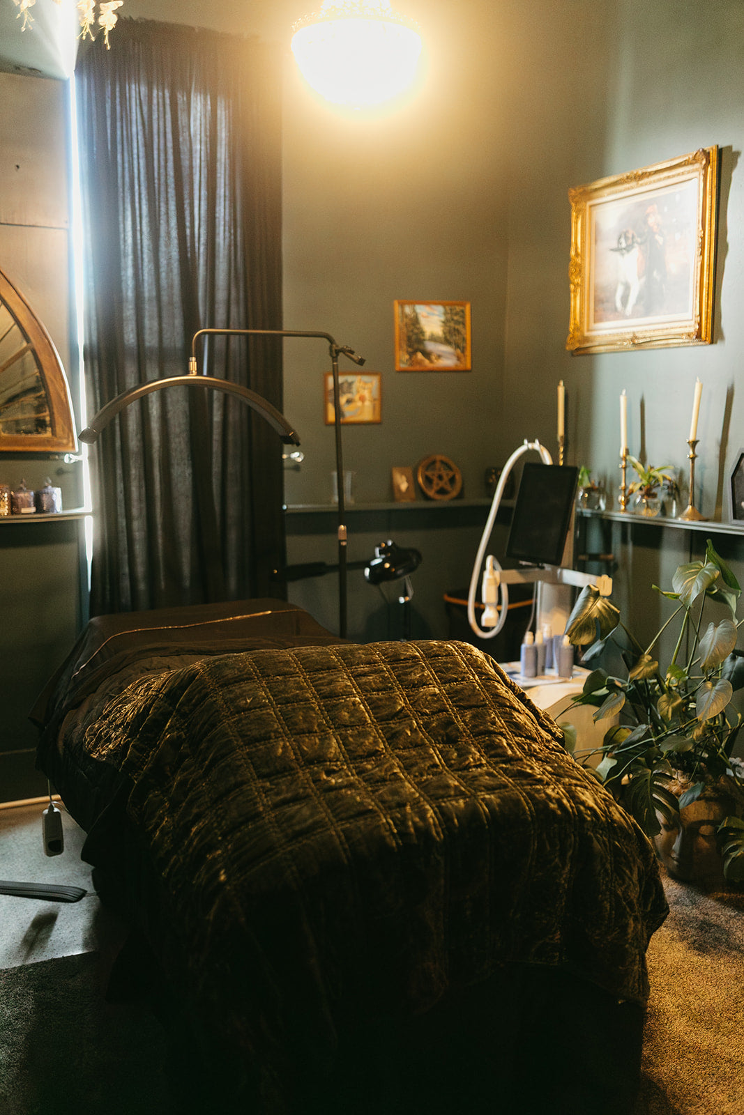 Darkly decorated room with a bed, lamp, and framed pictures on a wall.
