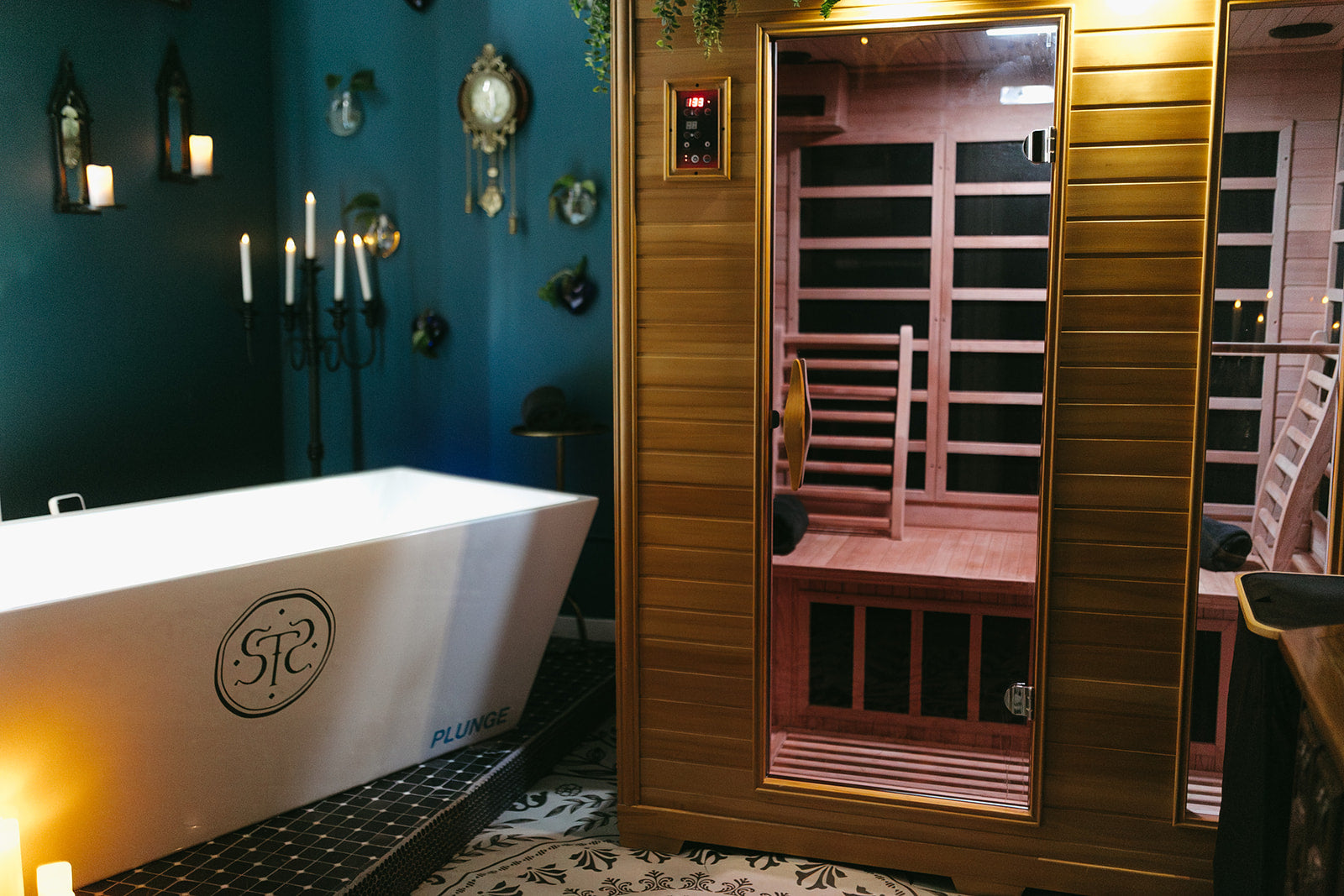 Infrared sauna with wooden interior and white bathtub with logo on a blue wall.
