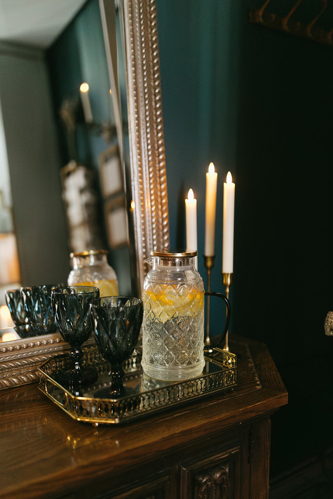 Decorative setting with candles, jars, and a mirror on a wooden surface.