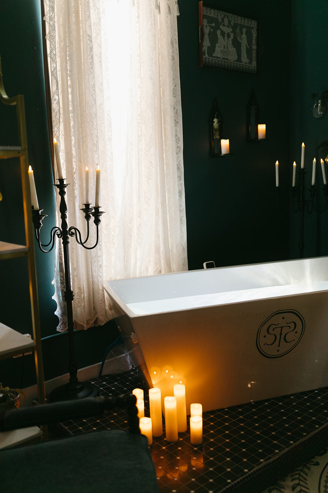 White bathtub with candles and a candelabra in a dimly lit room.